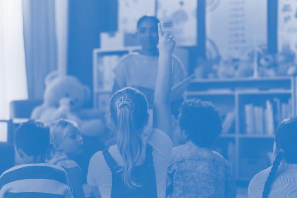 child raising hand in classroom
